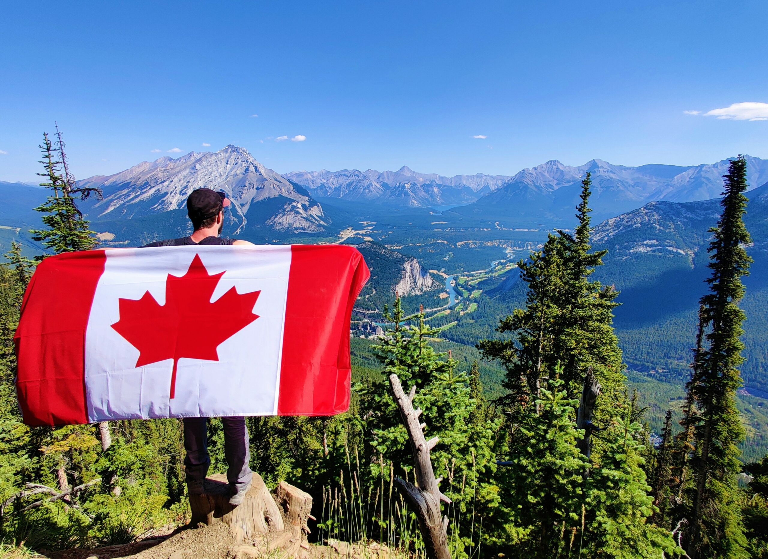 person holding Canada Day flag overlooking mountain