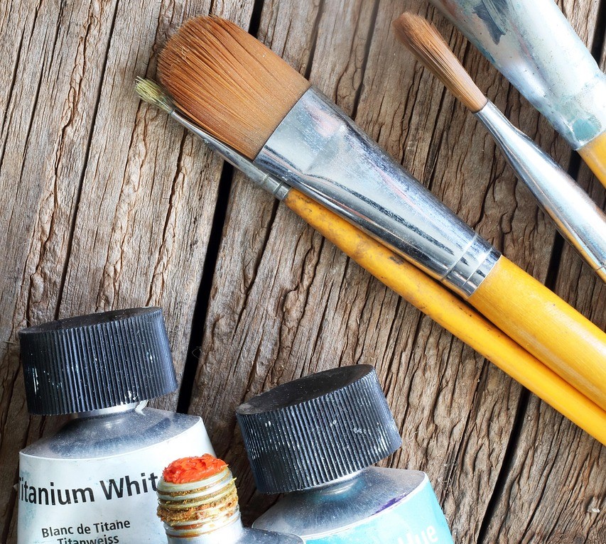 paint brushes and tubes of paint against wood background