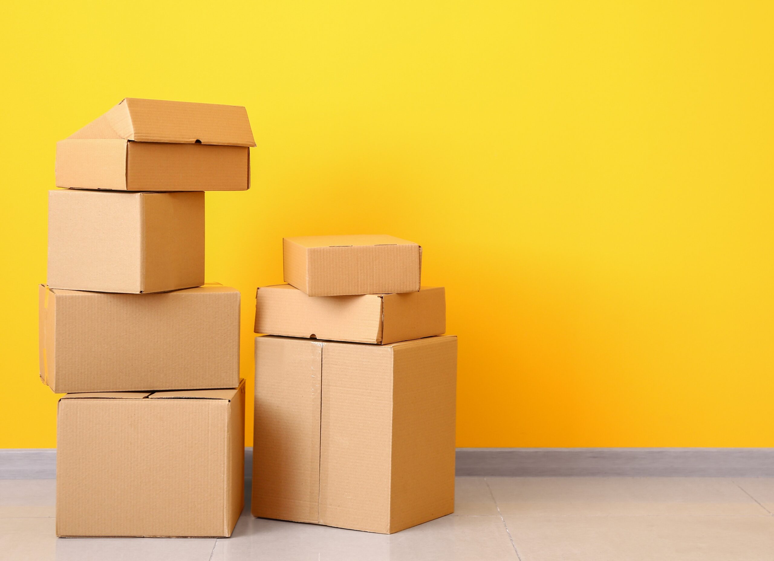 Stack of cardboard boxes against a yellow backdrop